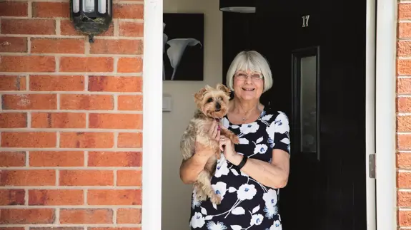 Older Lady Holding Dog In Doorway