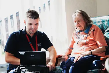 Man Helping Older Woman On Laptop
